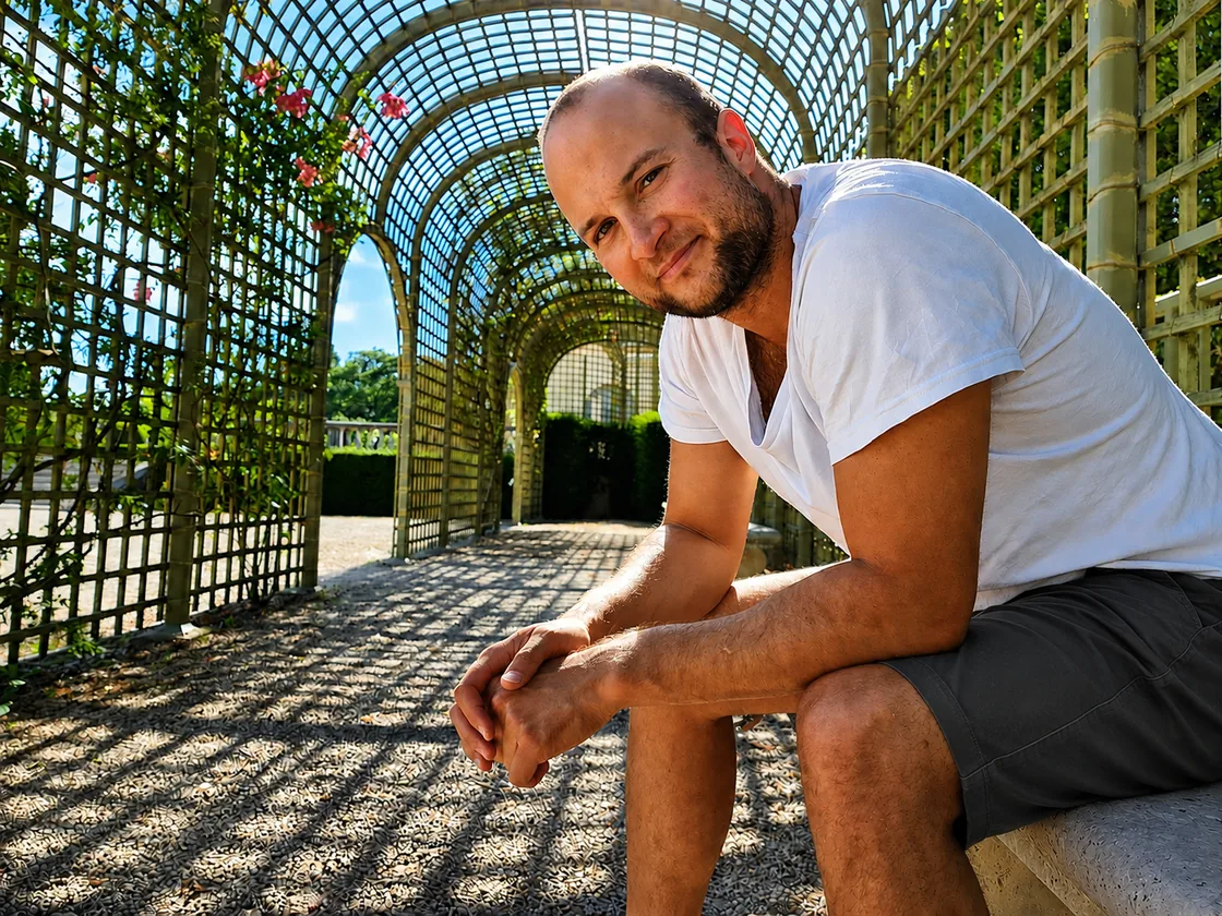 Sami Belhadj, founder of LayerLit Studio, photographed outdoors in a sunlit garden structure